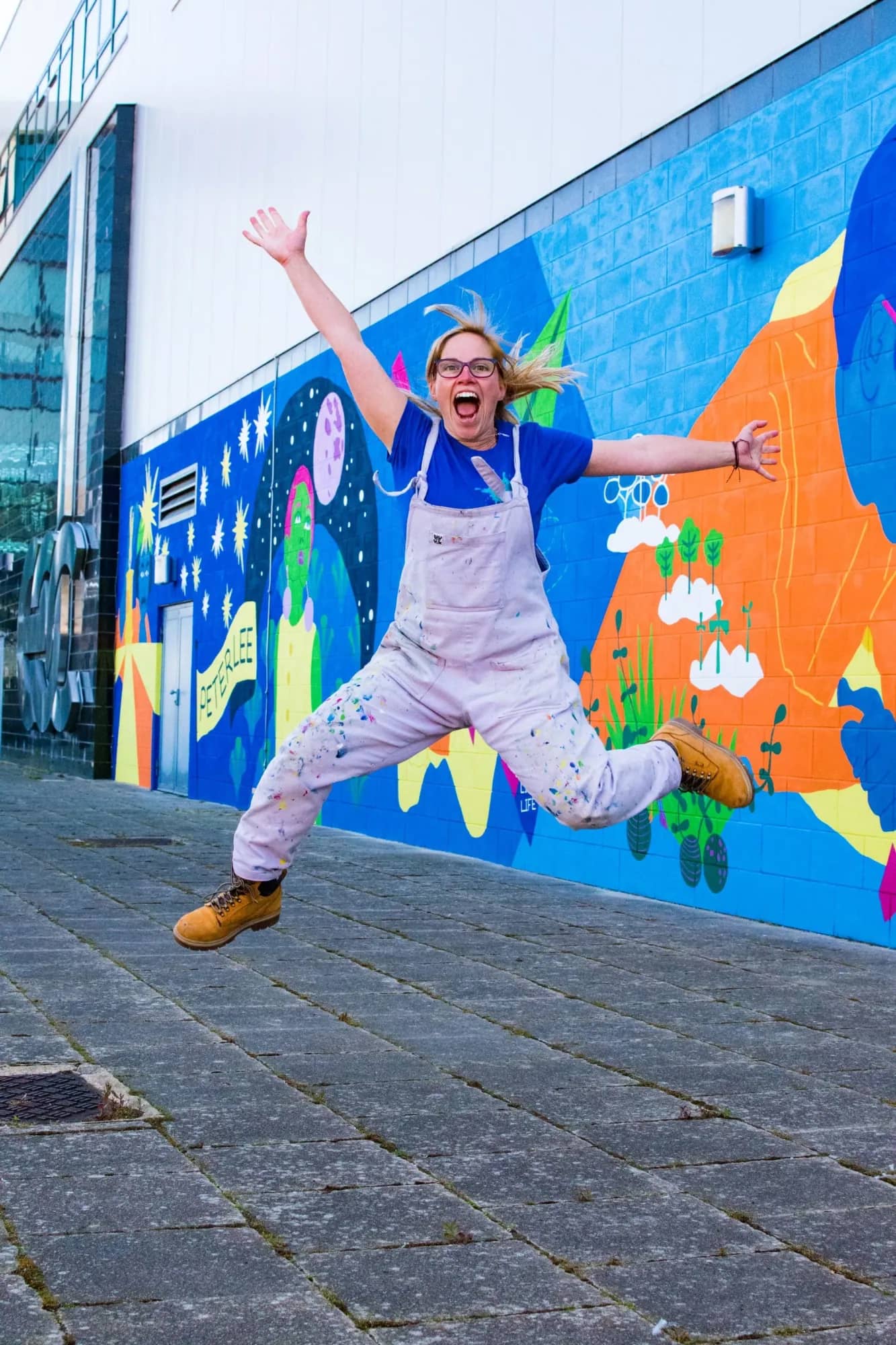 Hazel Oakes jumping for joy in front of a freshly painted mural