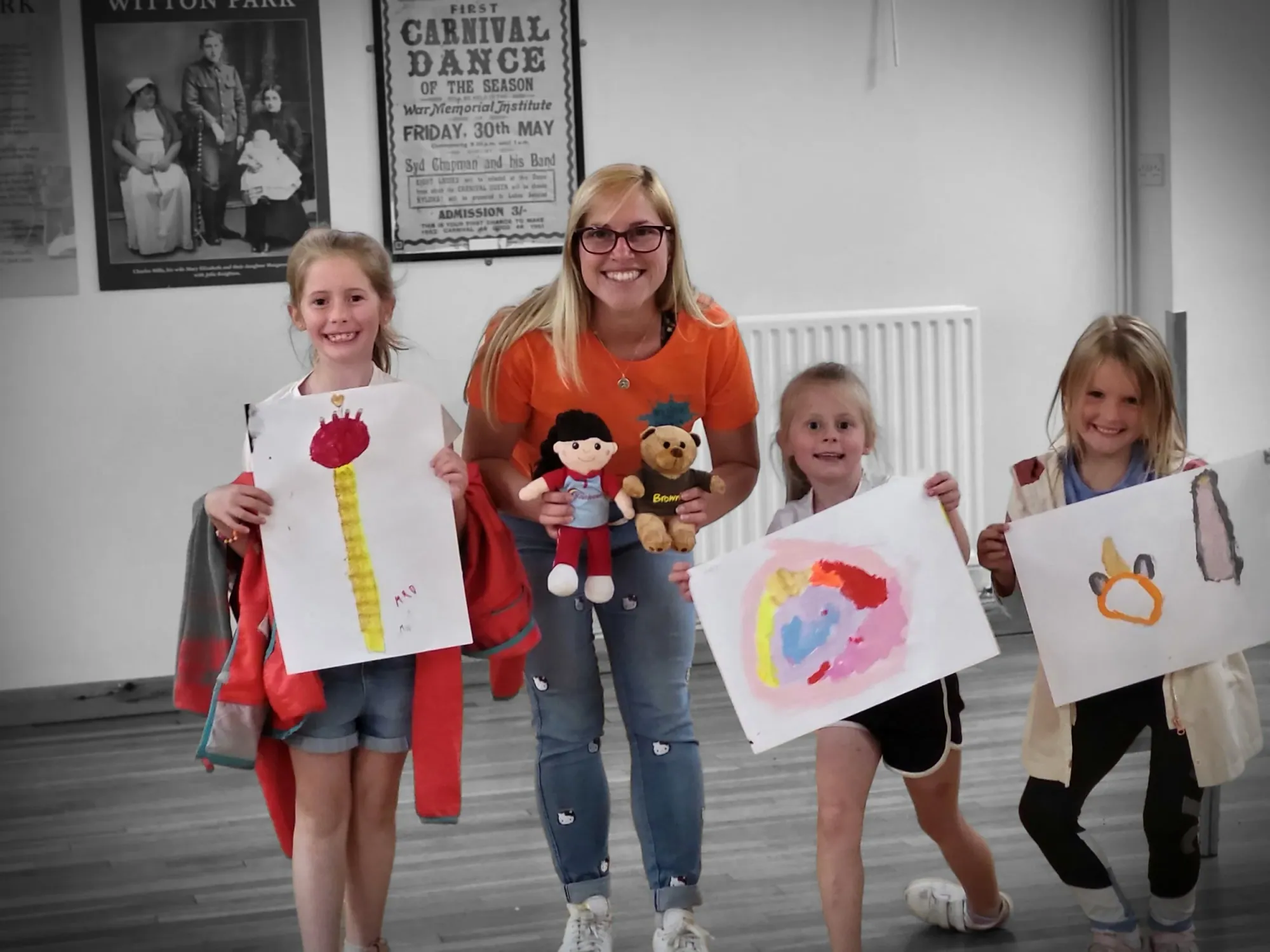 Hazel with young workshop participants holding up their drawings