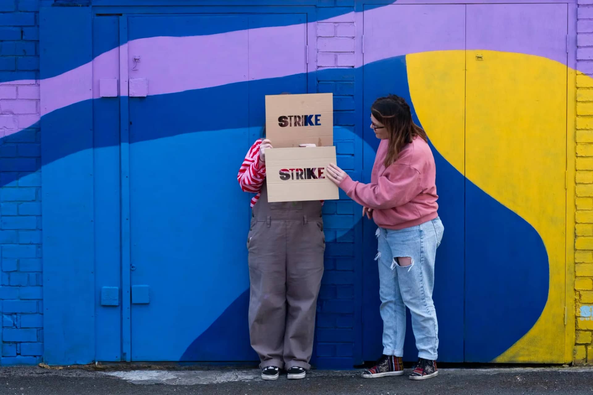 Holding the STRIKE sign in front of a finished wall