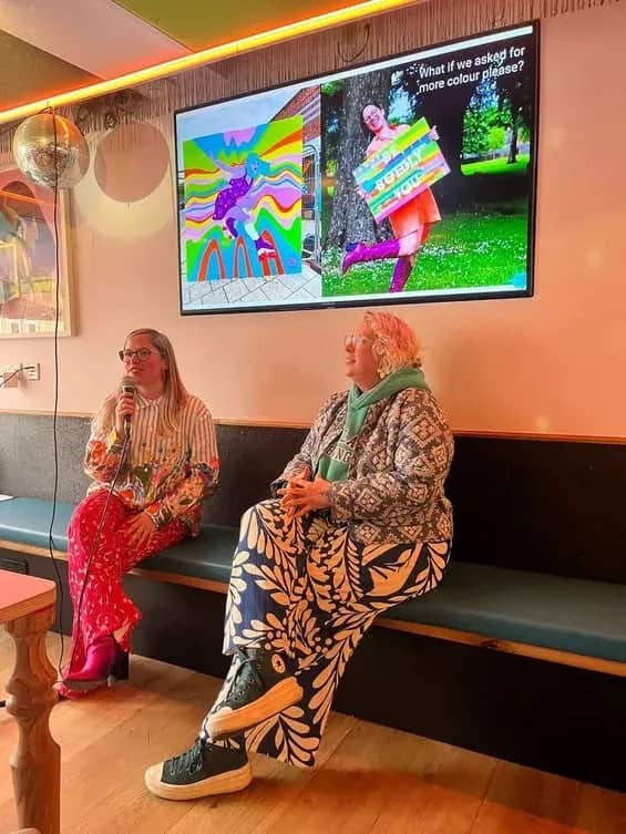Hazel and another artist on a panel in front of a screen